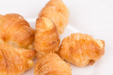 Fresh croissants on white plate.