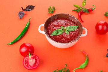 Bowl of tomato soup on a red background.