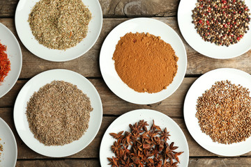 Different spices on plates, on old wooden table