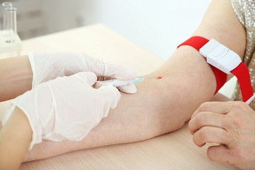 Nurse with syringe is taking blood for test in hospital