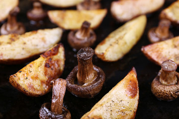 Baked potatoes with mushrooms and spices on pan close up