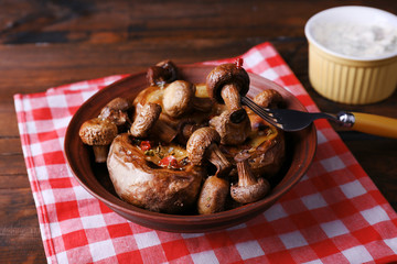 Baked potatoes with mushrooms in bowl and sauce