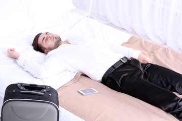 Tired man resting on bed in room