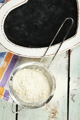 Fototapeta premium Sifting flour through sieve on wooden table, top view