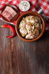Fried dumplings with onion and bacon in frying pan,