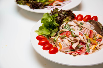 salad with pork meat served on a big white plate.