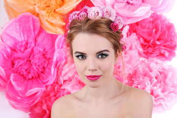 Portrait of young woman with flowers in hair on bright pink background