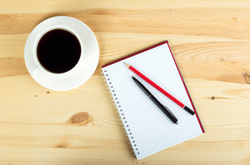 notebook pen and cup of coffee in wood table