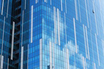 Glass facade of an urban building reflecting clouds