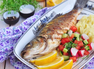 Fried fish served with mashed potato, lemon and vegetables salad