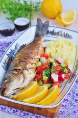 Fried fish served with mashed potato, lemon and vegetables salad