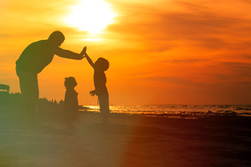 father and two kids playing at sunset beach