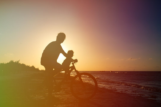 father and baby biking at sunset sea