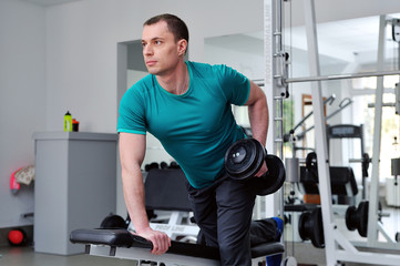 Fototapeta na wymiar Image of fitness guy in gym exercising with dumbbells