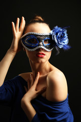 Portrait of beautiful woman with fancy glitter makeup and Masquerade mask on dark background