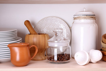 Kitchen utensils and tableware on wooden shelf