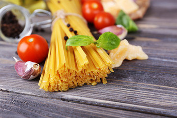 Raw pasta with cheese and vegetables on wooden background