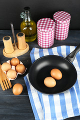 Still life with eggs and pan on wooden background