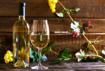 Obraz premium Bottle and glass of wine with grape on wooden background