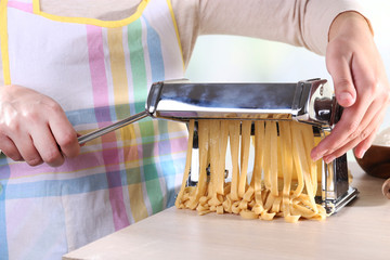 Woman making noodles with pasta machine, closeup