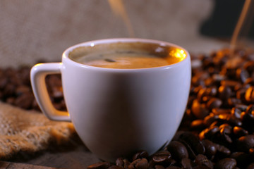 Cup of coffee with grains, closeup