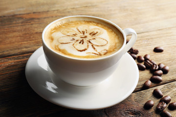 Cup of coffee latte art with grains on wooden background