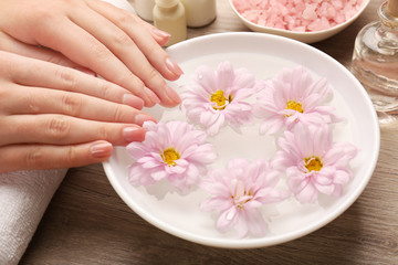 Obraz na płótnie Canvas Female hands and bowl of spa water with flowers, closeup