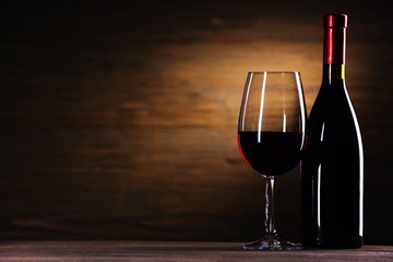 Wineglass and bottle on wooden background