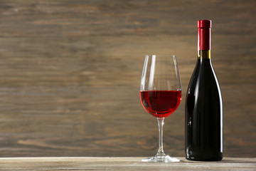 Wineglass and bottle on wooden background