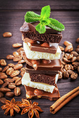white, dark, and milk chocolate with nuts - on wooden board