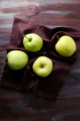 Green apples on wooden table with napkin, closeup