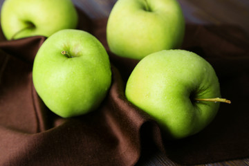 Green apples on wooden table with napkin, closeup