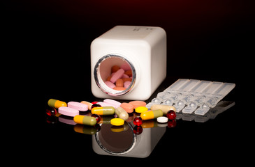 Colorful pills over dark background. Red Spotlight above