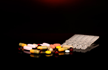 Colorful pills over dark background. Red Spotlight