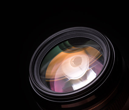 Photo lens closeup with colorful reflections. Black background