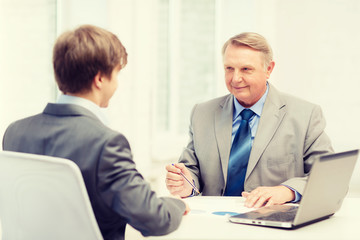 older man and young man having meeting in office