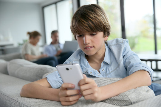 Teenage Boy Using Smartphone At Home