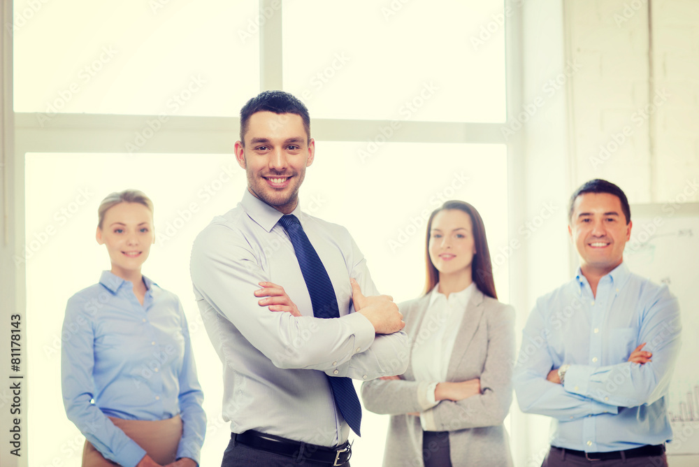 Sticker smiling businessman in office with team on back