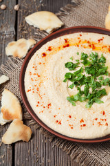 Creamy hummus in clay rustic plate served with pita