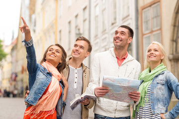 group of smiling friends with city guide and map