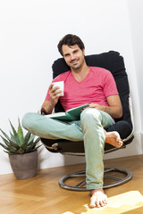 Man Sitting on Chair with Book and a Drink