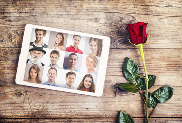 Tablet and a red rose. Studio shot on a wooden floor backround.
