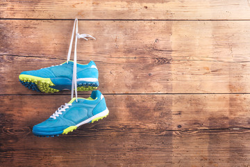 Sports shoes hang on a nail on a wooden fence background
