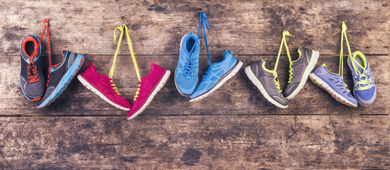 Sports shoes hang on a nail on a wooden fence background - obrazy, fototapety, plakaty