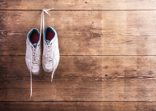 Sports shoes hang on a nail on a wooden fence background