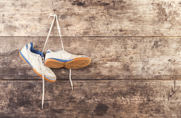 Sports shoes hang on a nail on a wooden fence background