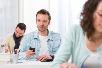 Fototapeta premium Young attractive student using his mobile during classes