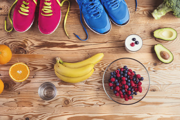 Running shoes and healthy food composition on wooden background