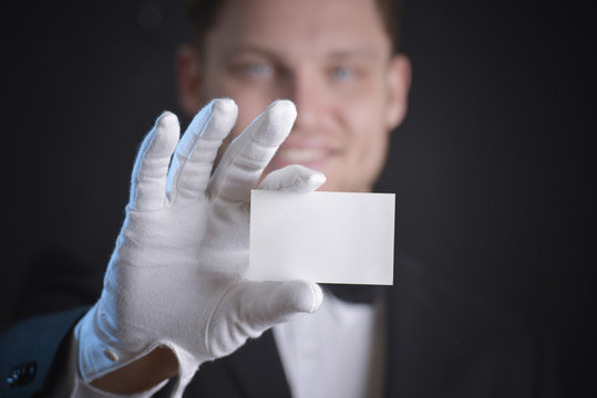 Butler Wearing White Gloves And Holding A Business Card