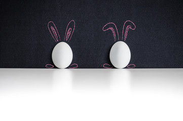 Two white easter eggs painted with rabbits ears on a chackboard - 81185700